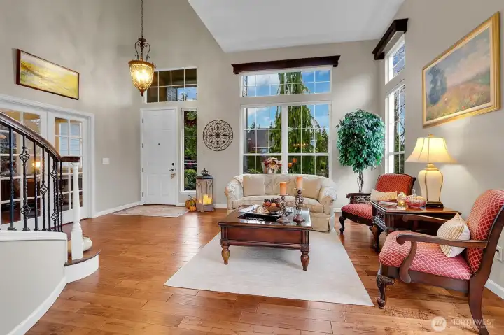 Grand foyer/formal living room with curving staircase, vaulted ceilings, skylights, and hardwood floors.