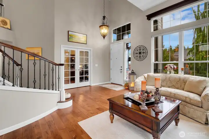 Grand foyer/formal living room with curving staircase, vaulted ceilings, skylights, and hardwood floors.