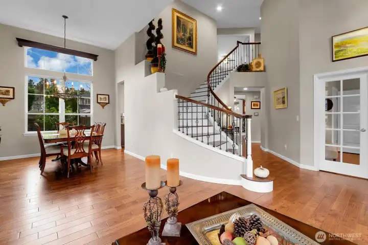 Grand foyer/formal living room with curving staircase, vaulted ceilings, skylights, and hardwood floors.