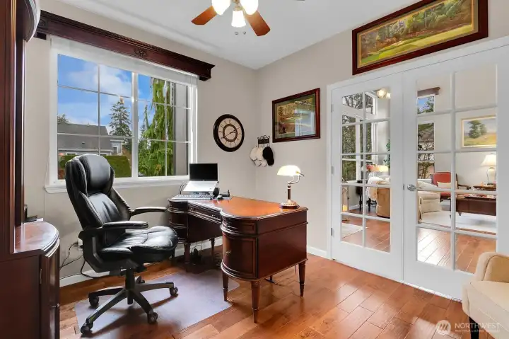 Bright office on main floor with french doors and hardwood floors.