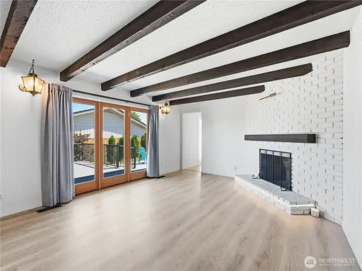 Cozy family room featuring exposed wood beams and a dramatic floor-to-ceiling painted brick fireplace. Cozy family room featuring exposed wood beams and a dramatic floor-to-ceiling painted brick fireplace.