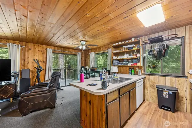 Kitchen with a large eating bar, plus a dining area with slider to deck.
