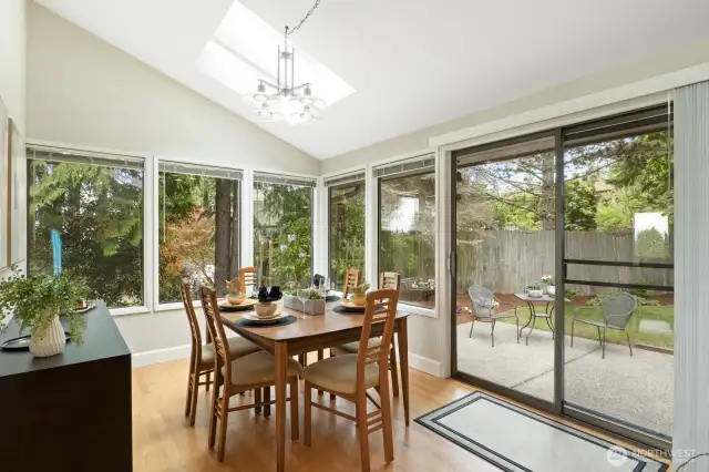 Dining area with sliders to backyard and walls of windows to bring the outside in.
