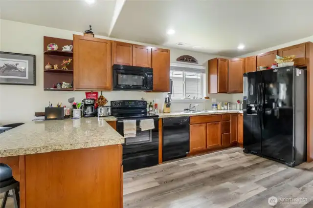 Nice open kitchen with lots of counter space, lots of cupboards, all black appliances and to the right a custom built China buffet and cabinets for extra storage.