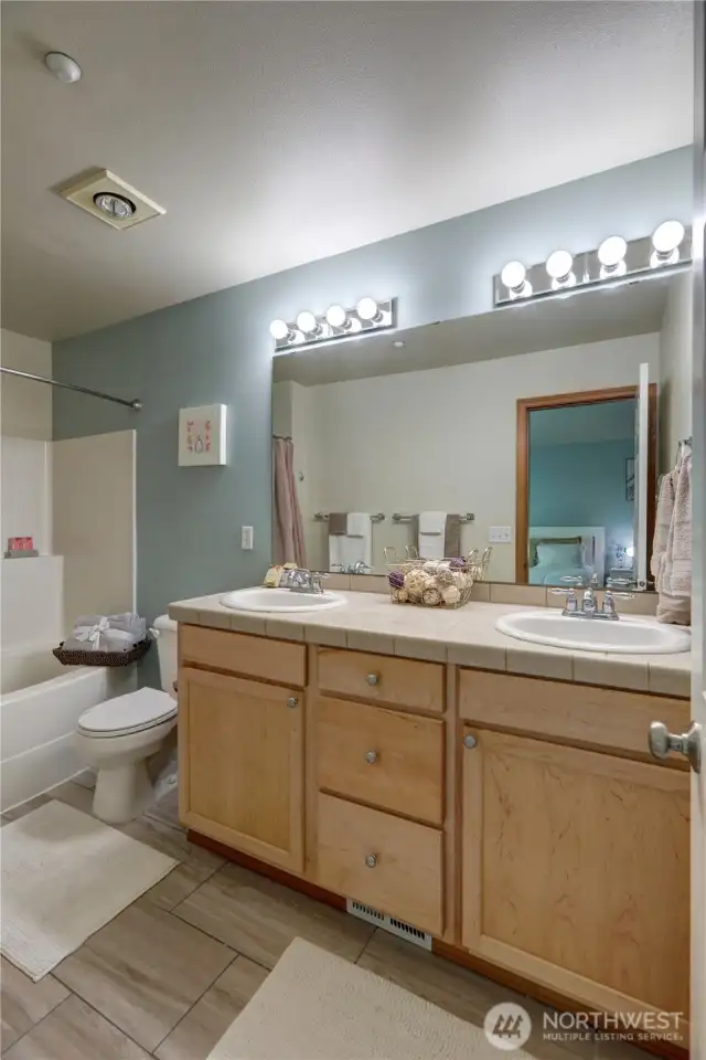 The primary bedroom suite is truly a retreat —offers a private en-suite bathroom that features dual sinks, a cabinet vanity, a large soaking tub, and shower.