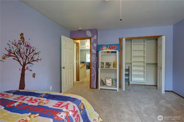 Kids room with a large built-in closet organizer featuring plenty of shelving