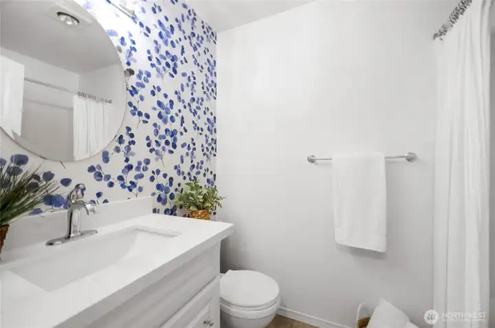 hall bathroom with updated cabinets and quartz countertops. The wallpaper is peel and stick and is easily removable.