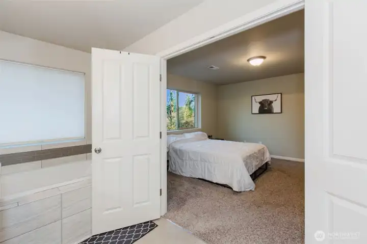 View into primary bedroom and soaking tub in 5pc  bathroom