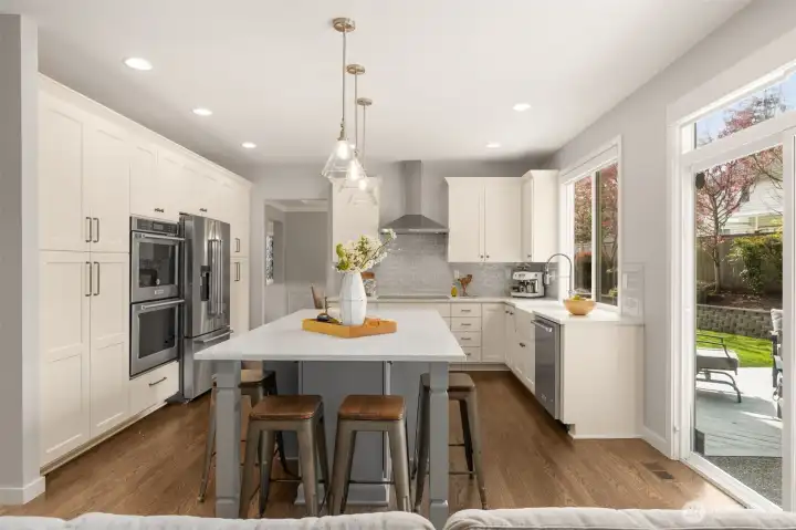 Chef-inspired kitchen with custom cabinetry, quartz countertops, deco tile backsplash, double oven, convection cooktop, counter depth refrigerator.