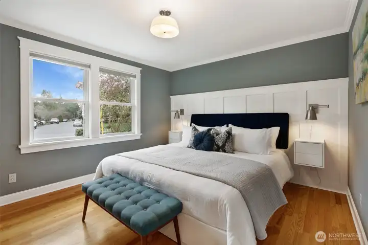 Southeast-facing primary with dimmable lighting, custom wainscoting, and great morning light. (Lights and side tables stay with the home).