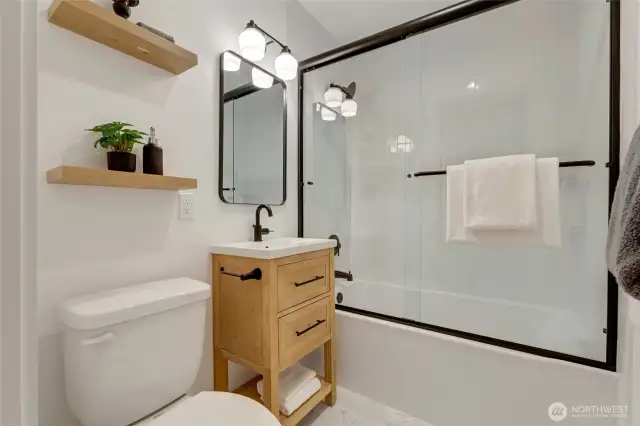 Primary suite offers a full bath with beautiful tile, and all new materials including and not limited to plumbing fixtures, lighting, cabinetry, tub, tile, shelving, and accessories.