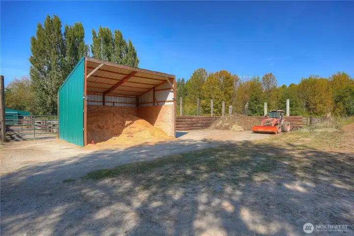 Shavings bin with manure storage area to the right with cattle pens beyond.