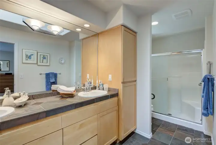 Primary bath has tile floors and counters, walk-in shower, skylight and dual vanity.