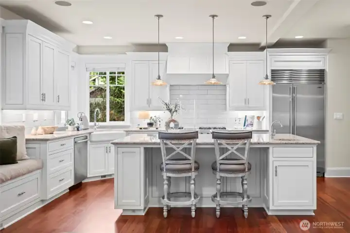Luminous and impeccably appointed, the kitchen is a masterclass in coastal elegance. Crisp white cabinetry and a classic subway tile backsplash perfectly complement the professional-grade suite of Sub-Zero and Viking appliances.