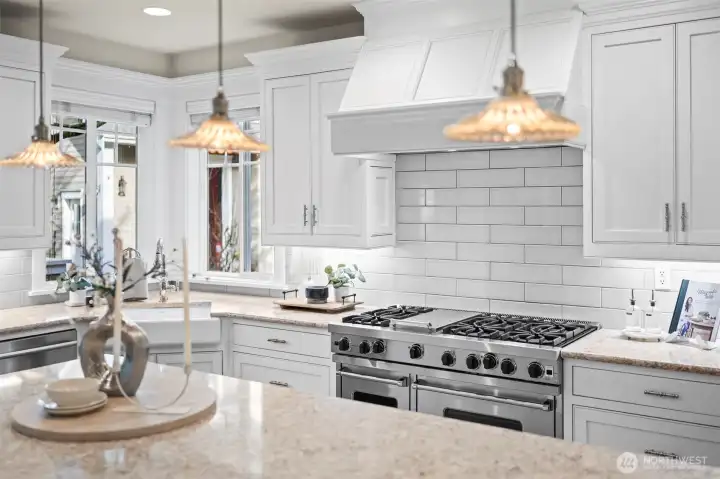 Every element is curated for the culinary enthusiast, from the expansive stone island to the deep farmhouse sink and high-end fixtures. This space serves as the home's primary gathering point, blending artisanal charm with modern high-performance utility.