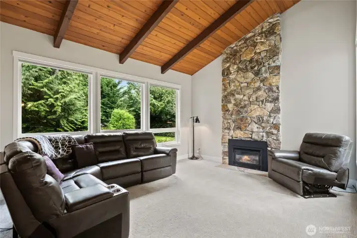 Living room off foyer impresses with soaring wooden ceiling and stone gas fireplace.