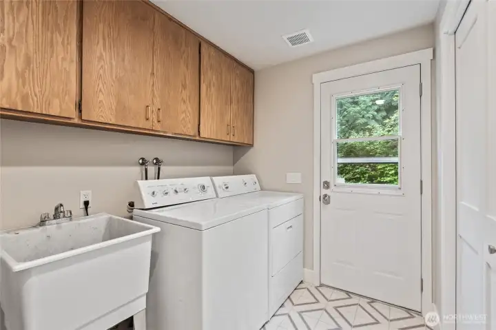 Large laundry/mud room with sink, storage and door to the yard.