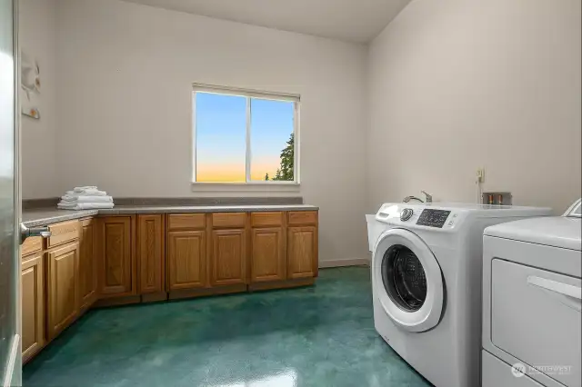 Large laundry room with laundry tub, folding counters and storage.
