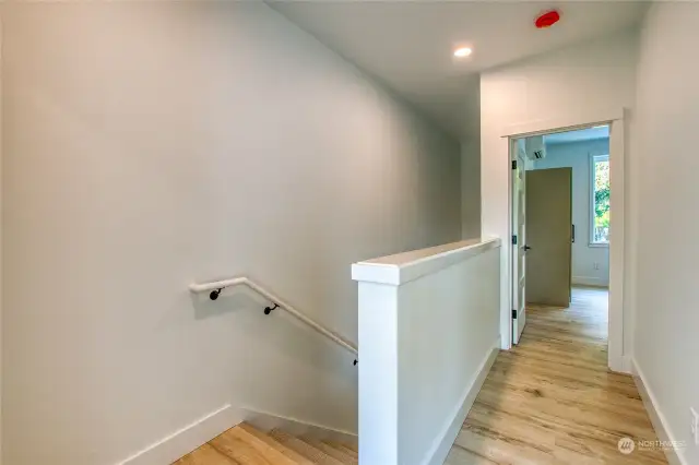 The hallway connects two upstairs ensuite bedrooms, with a laundry area conveniently located at the top of the stairwell.