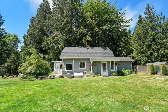 A beautiful fully fenced lot with a firepit, garden beds and a wooded area.