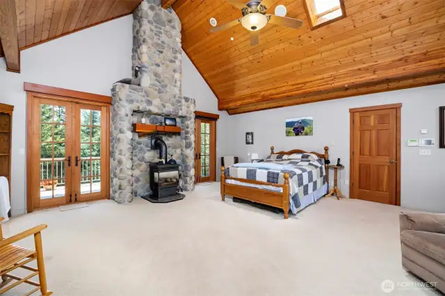 The primary suite is very spacious and has a gas freestanding stove. There is a private deck with French doors that overlooks the large lawn. The closed door leads to one of the 2 large walk-in closets.