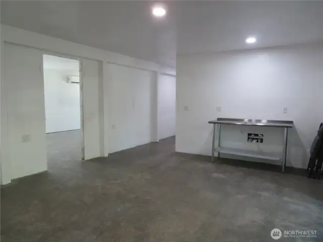 Larger bedroom in lower level, dining area, ktichen against the wall with hookups for stove, refrigerator and sinks.  Middle hallways takes you to the laundry room and the .75 bath space with all of the hookups of laundry and bathroom.