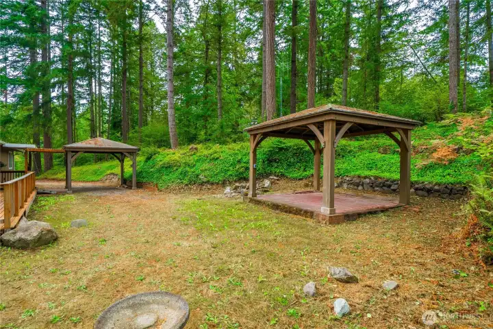 Another angle of the property, showing the gazebo, natural landscaping, and carport.