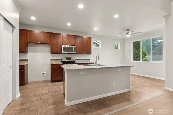 This kitchen was clearly designed for real life. The island anchors the space with granite countertops and a sink that keeps prep and cleanup social instead of isolated. Tile floors handle traffic with ease, while the eat-in area sits in front of a huge picture window that brings in serious daylight. Two additional high windows in the nook free up wall space for a hutch, storage, or whatever setup fits your routine. Bring your own refrigerator, the ice and water hookup is already in place. A contemporary ceiling fan keeps the casual dining area flexible, whether it’s meals, homework, gaming, or an extra seating zone when the house is full.