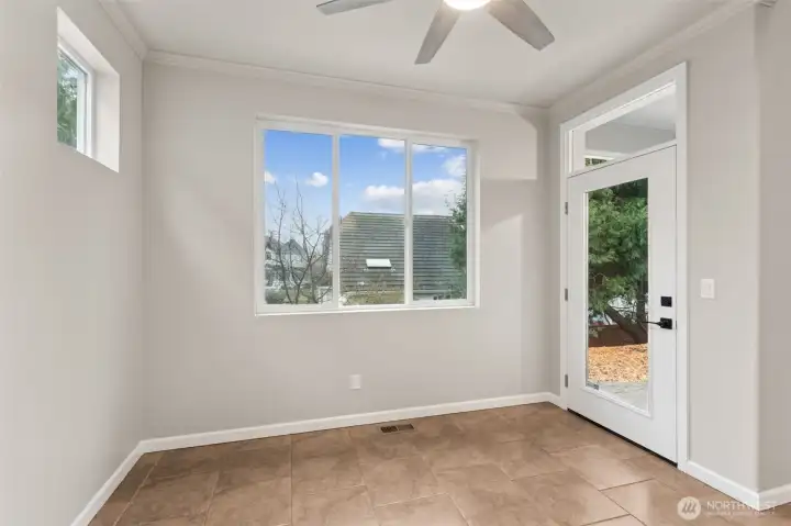 A glass door with an overhead accent window opens straight to the covered back patio, which makes grilling and outdoor dining feel effortless. Tile floors are exactly what you want at an indoor outdoor transition point, durable and easy to clean. Contemporary black door hardware adds contrast, while rounded wall corners and crown molding painted to match the walls keep the look soft and understated. It’s casual, intentional, and surprisingly elevated.