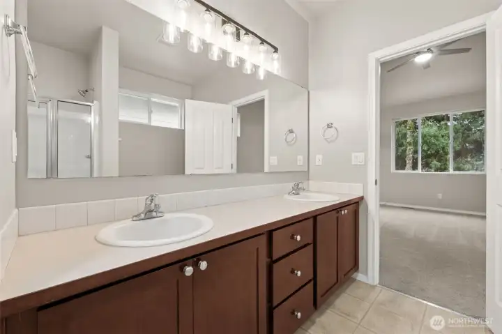 An extra long vanity with dual sinks gives everyone their own space, while the full length mirror and new sconce lighting keep things bright and functional. The cabinetry offers generous storage, tile floors hold up to daily use, and the five piece layout delivers real breathing room. Add in tall ten foot ceilings and the space feels open, calm, and luxurious.