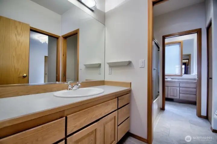 Intelligently designed main bath with vanity, shower, and additional vanity between the two bedrooms, able to be closed off.  Porcelain tile flooring and solar tube.