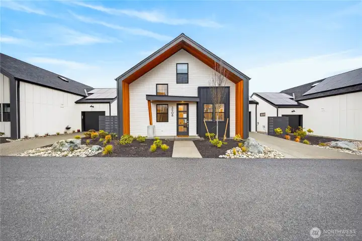 Wood wrapped entry and full yard landscaping with trash can screening.