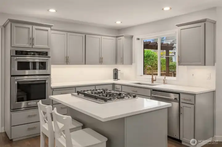 Kitchen features gas range with down draft, slab quartz counters with under-mount stainless trough sink.