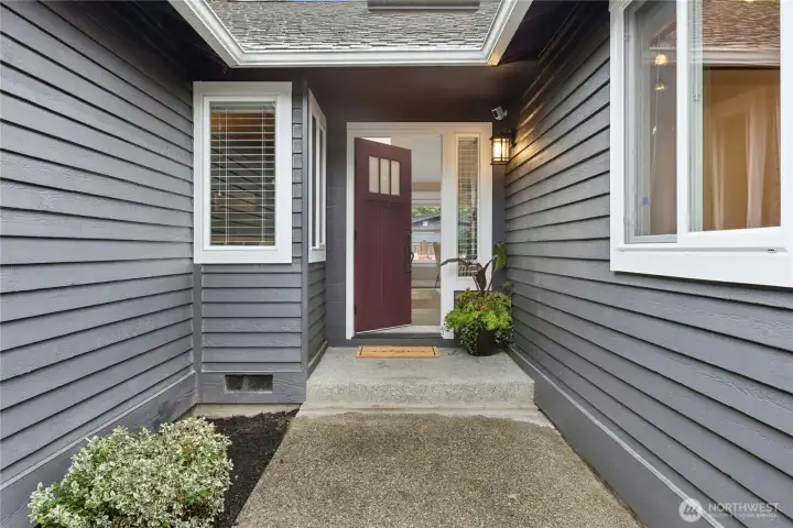 Inviting covered front entry with Craftsman-style door, updated exterior lighting, and modern designer finishes creating a warm first impression.