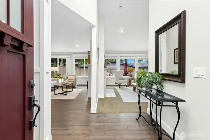Bright and welcoming entry foyer with engineered hardwood flooring, custom millwork, soaring ceilings, and open sightlines into the main living spaces.