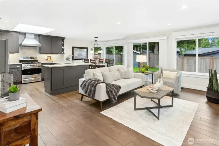 Stunning open-concept living area featuring engineered hardwoods, expansive windows, abundant natural light, and seamless flow between the kitchen, dining, and family room.