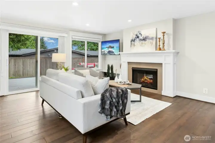 Spacious great room with custom fireplace surround, large picture windows, recessed LED lighting, and direct access to the expansive composite deck for indoor-outdoor living.