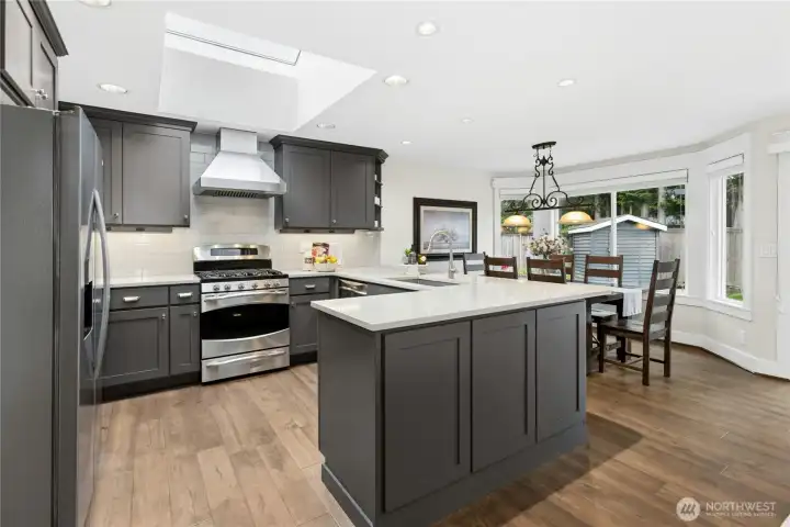 Beautifully remodeled chef’s kitchen featuring quartz countertops, custom soft-close cabinetry, skylight, stainless steel appliances, and oversized entertaining island.