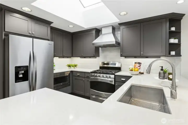 Designer kitchen filled with natural light from oversized skylight, showcasing premium cabinetry, quartz surfaces, under-cabinet lighting, and abundant prep space