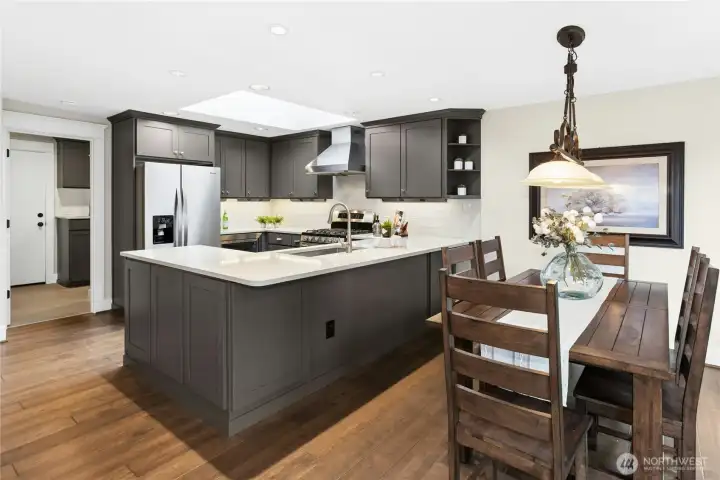 Open-concept kitchen and dining area designed for entertaining with oversized island seating, designer lighting, and seamless connection to the living spaces.