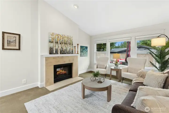 Elegant formal living room featuring vaulted ceilings, marble fireplace surround, custom millwork, and oversized windows creating a warm and inviting atmosphere.