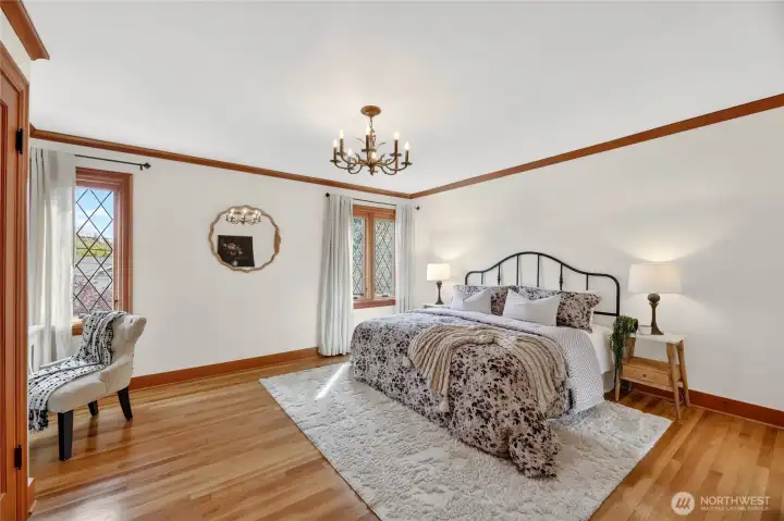 The large upstairs Primary bedroom with double door closet, beautiful wood floors, double-paned leaded glass windows and attached primary bath. Stay cool on hot days - this home has A/C too!