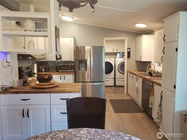 Picture of the Spacious Open Bright Kitchen with All White Cabinets, Newer Counter Tops, Newer Stainless Appliances, Interior Paint and Vinyl Plank Flooring Looking at the Dining Room.