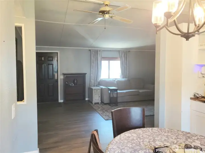 A Picture from the Huge Living Room Looking at the Front Entry Door Showing New Interior Paint, White Painted Trim and Vinyl Plank Flooring.