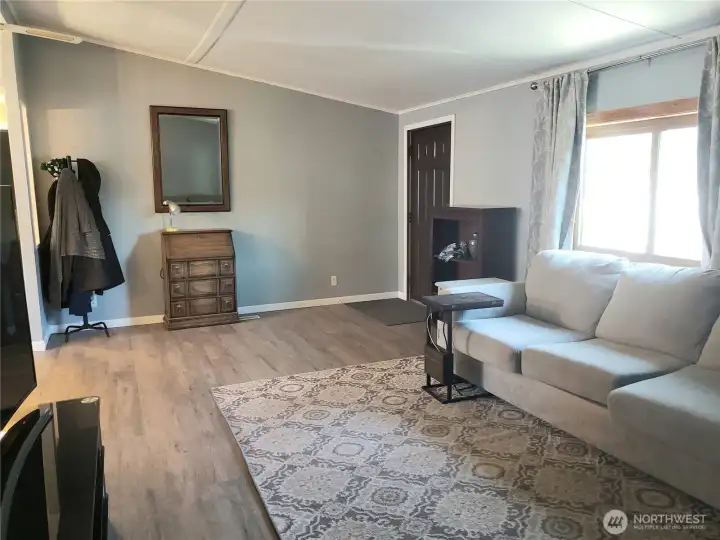Another Picture from the Huge Living Room Looking into the Living Room Front Entry Door Showing New Interior Paint, White Painted Trim and Vinyl Plank Flooring.
