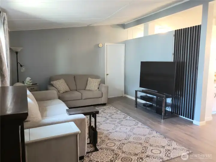 Another Picture from the Huge Living Room Looking at the Primary Bedroom Showing the Storage Closet beside the TV with New Interior Paint, White Painted Trim and Vinyl Plank Flooring.