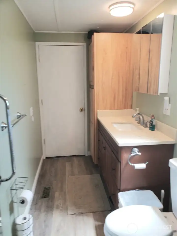 Picture of the Large Primary Master Bathroom with New Quartz Vanity, Sink, Faucet, Toilet, Interior Paint, White Painted Trim, and Vinyl Plank Flooring.