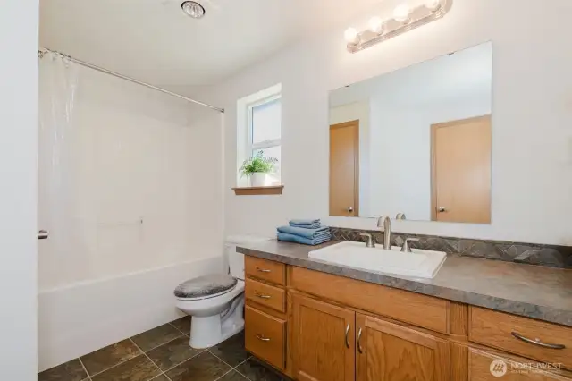 Upstairs guest bath with shower/tub combo and large vanity.