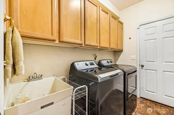 Main floor laundry room with built in cabinets and utility sink, perfect mud room located between the garage and living spaces