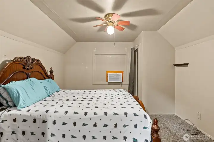 Upstairs bedroom with additional wall ac unit and ceiling fan.